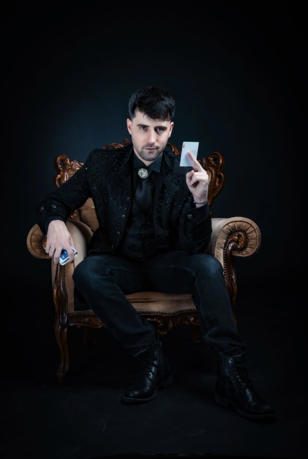 magician holding a card sat in a chair